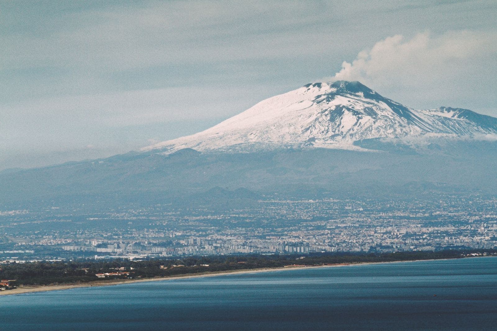 Etna innevato con la città di Catania e il mare visti dall'alto